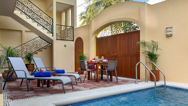 Zona de piscina con sillas de descanso, una mesa de comedor con sillas y una escalera.