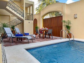 A pool area with lounge chairs, a dining table with chairs, and a staircase. - Newly built 1 bdrm, luxury apartment. Quiet and yet close to everything. (Puerto Morelos)