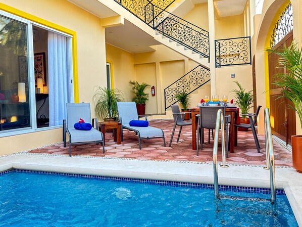 A poolside area with lounge chairs, a table with drinks, and a staircase leading to an upper level. - Newly built 1 bdrm, luxury apartment. Quiet and yet close to everything. (Puerto Morelos)