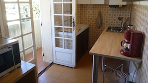 Une cuisine compacte dotée d’un plan de travail en bois, d’une machine à café rouge et d’un pare-feu en carreaux.