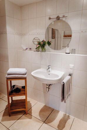 Bathroom features a central sink, round mirror, and a stool with a towel.