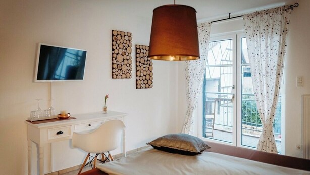 Un dormitorio con cama, escritorio, silla, televisor y ventana con cortinas.