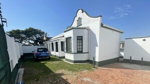 Un edificio blanco con un camino de ladrillo que lleva a un automóvil estacionado al frente.