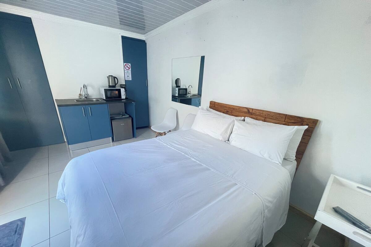 Een hotelkamer met een groot bed, een bureau, een stoel, een magnetron, een waterkoker en een kleine koelkast.