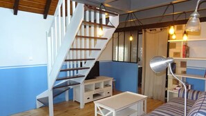 A room with a wooden staircase, a striped sofa, a white coffee table, and a desk with a lamp. - Kerheol Pointe de la Torche - 200 m from the beach (Plomeur)