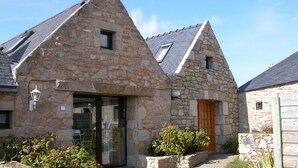 A stone building with a sloped roof, a glass door, and a small window. - Kerheol Pointe de la Torche - 200 m from the beach (Plomeur)