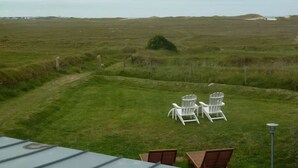 A grassy field with a path leading to white chairs and a table, suggesting an outdoor seating area. - Kerheol Pointe de la Torche - 200 m from the beach (Plomeur)