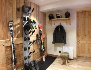 Een skiopslagruimte met ski's, stokken en helmen op planken en haken.