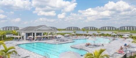 A resort with a large swimming pool, lounge chairs, and a covered pavilion.