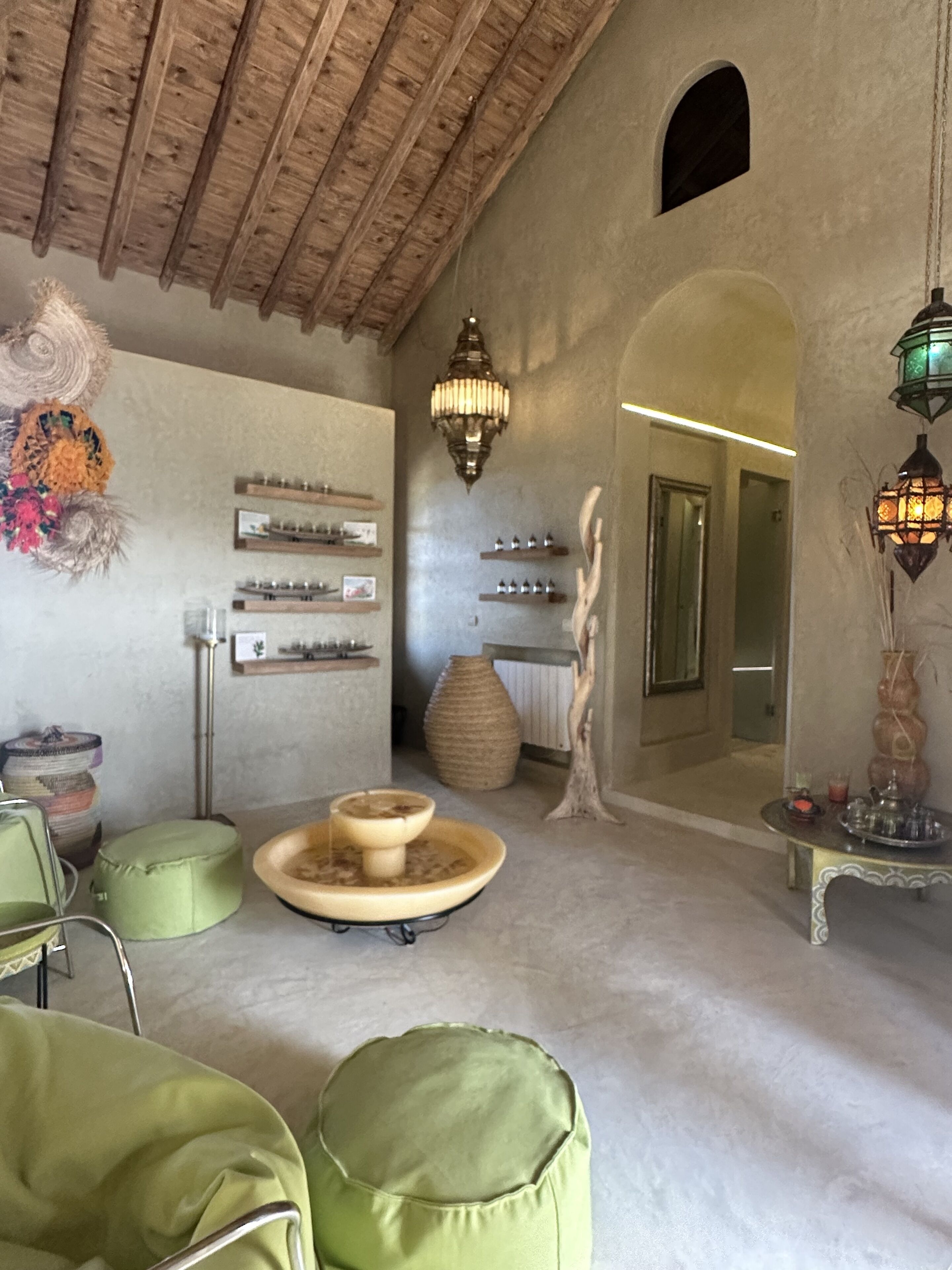 A cozy room with a rustic ceiling, a round table with a candle, and a mirror reflecting the room.