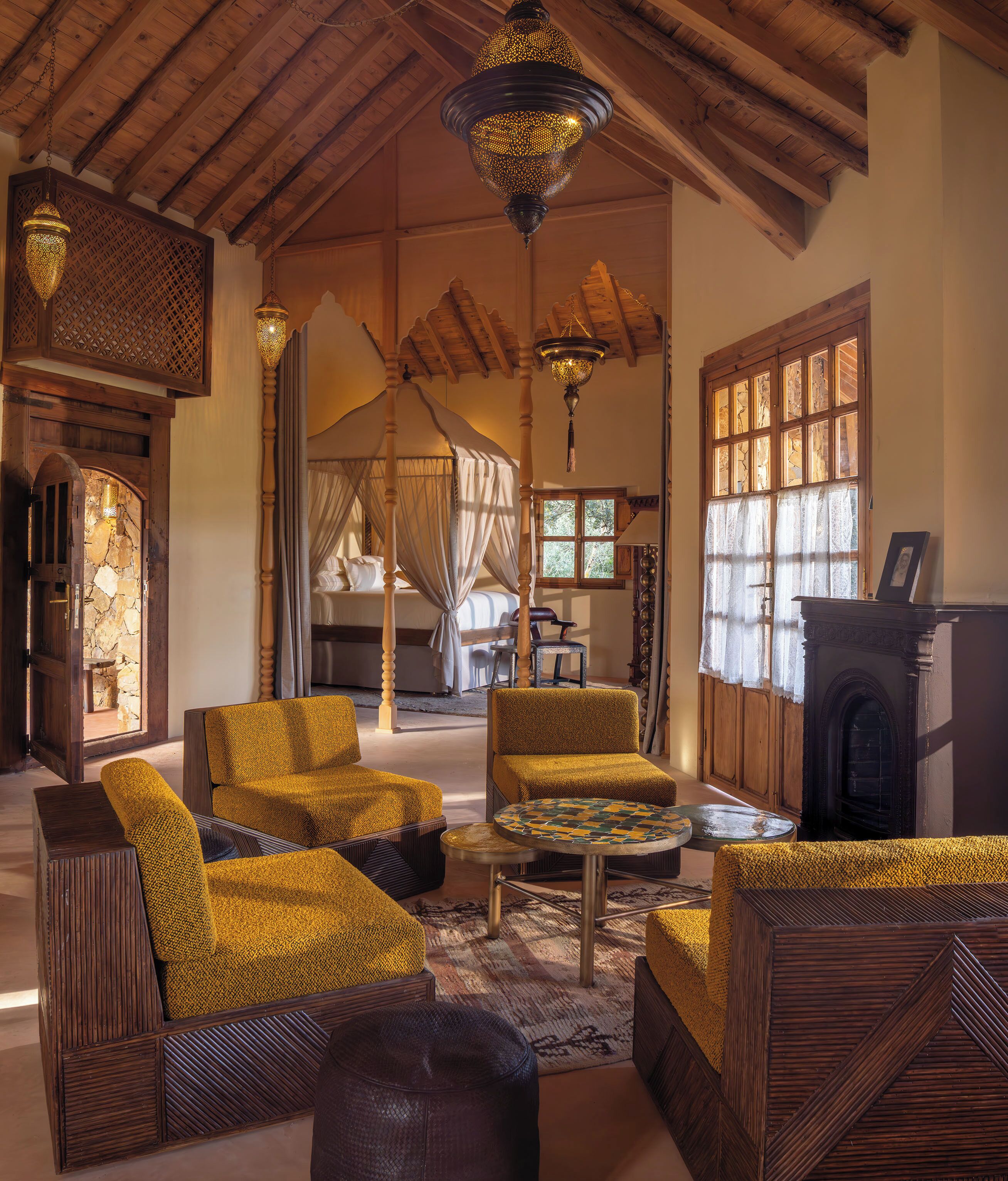 A cozy room with a four-poster bed, wooden furniture, and a fireplace.