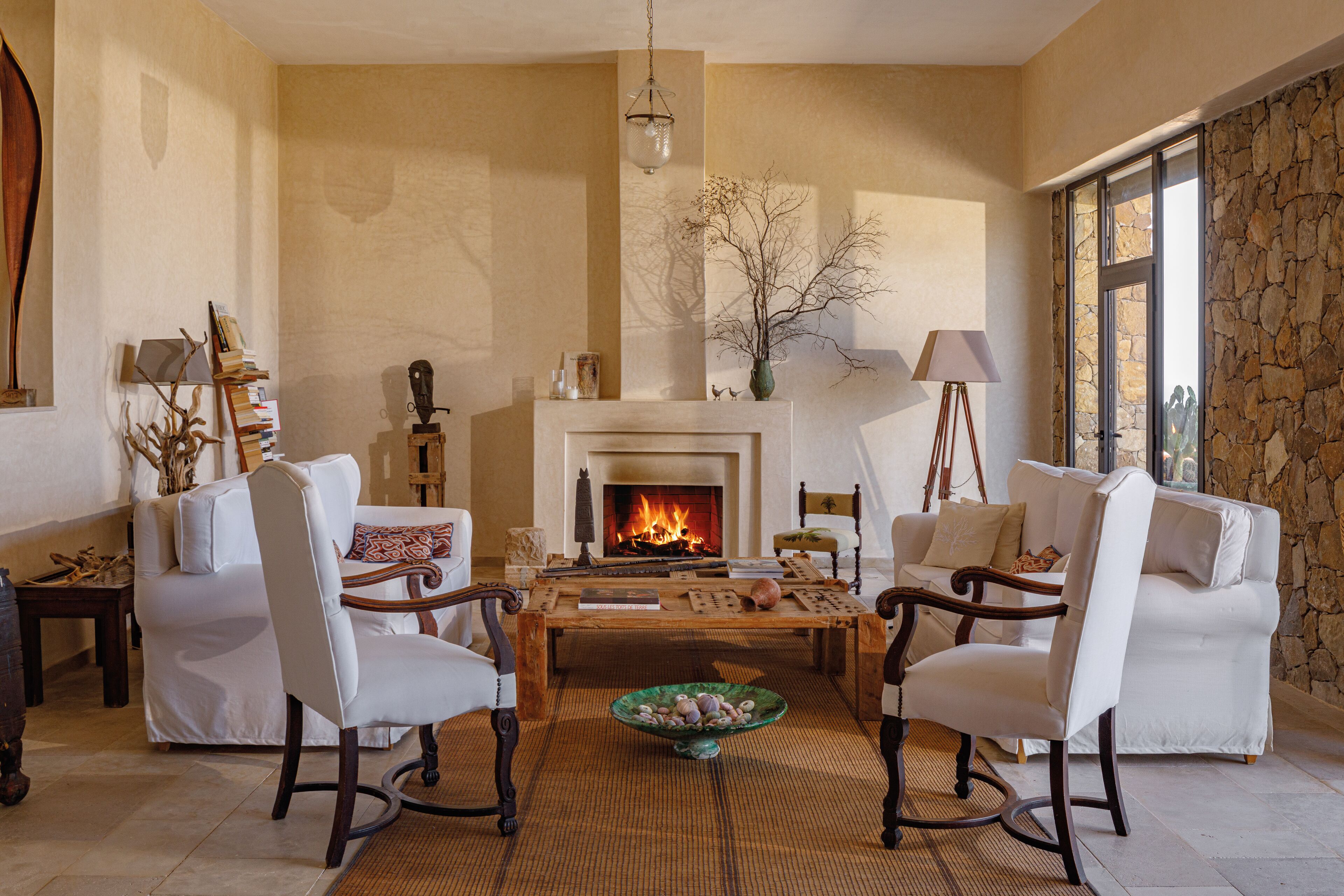 A cozy living room with a fireplace, white sofas, and a coffee table.