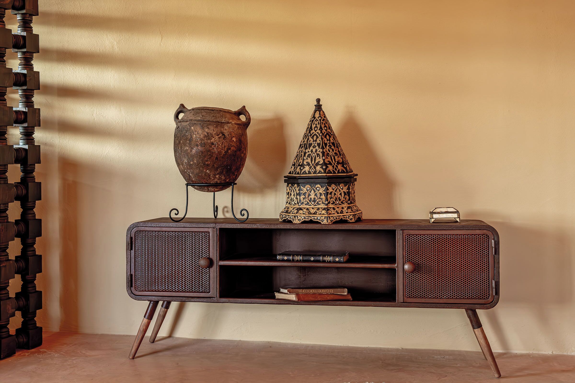 A vintage-style console table with two decorative items: a pot and a lantern.