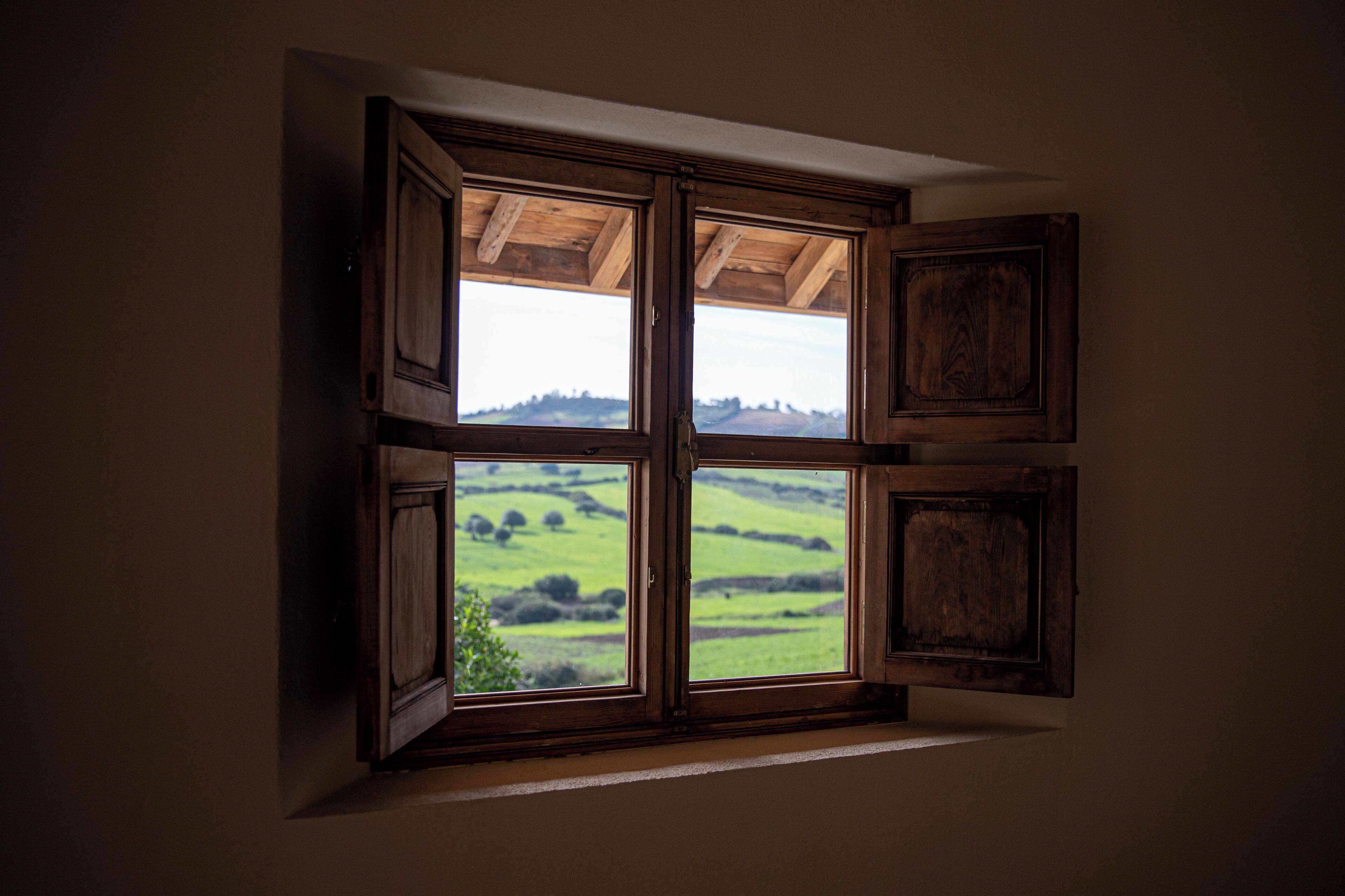 A room with a large window offering a view of a green landscape.