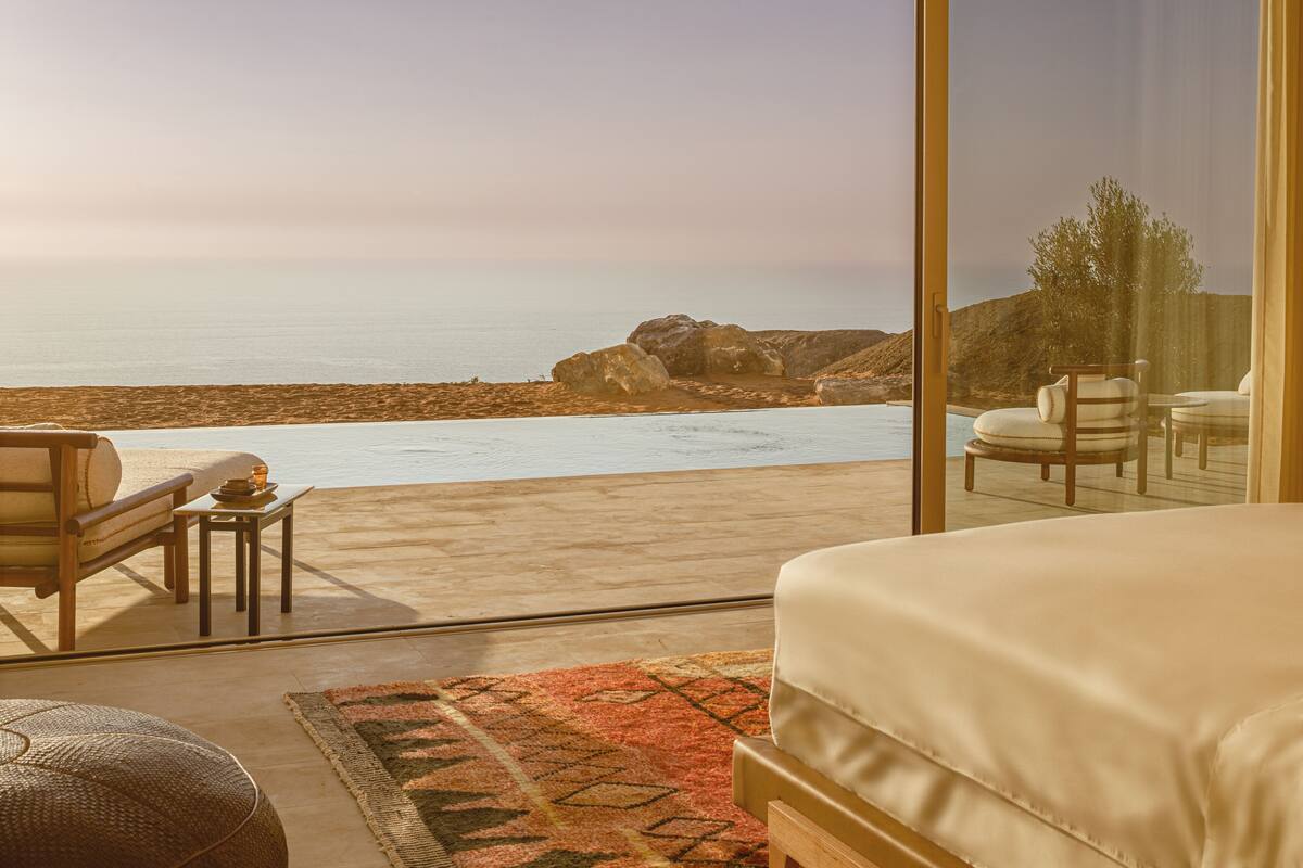 Une chambre avec une grande fenêtre donnant sur une plage et une piscine.
