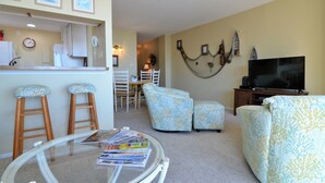 A living room with a glass coffee table, two bar stools, a sofa, and a television. - AMAZING OCEANFRONT CONDO - 809 Brandywine House, Sea Colony, Bethany Beach (Bethany Beach)