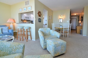 Cozy living space with a sofa, armchairs, dining table, and kitchen area.
