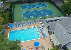 Propiedad residencial con piscina, canchas de tenis y zona de estar al aire libre.
