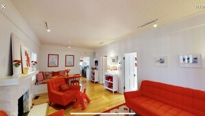 Un salón espacioso con chimenea, sofás rojos y una zona de comedor con una cocina al fondo.