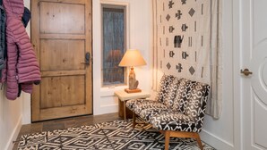 A hallway with a wooden door, a patterned rug, a bench, and a wall with decorative patterns. - Sun Valley, Idaho / Downtown Ketchum Penthouse / Views, Ski, Sun, Prime Location (Ketchum)