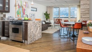 A modern kitchen with a central island, stainless steel appliances, and a dining area with a round table and chairs. - Sun Valley, Idaho / Downtown Ketchum Penthouse / Views, Ski, Sun, Prime Location (Ketchum)