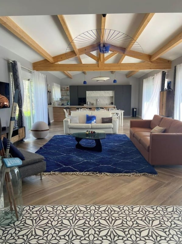 Un salon moderne avec un plafond en bois, une table basse centrale et un canapé.
