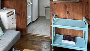A compact kitchen with wooden cabinets, a white refrigerator, a sink, and a blue storage cart. - Adorable Cape Cottage Near Kingsbury Beach (Eastham)