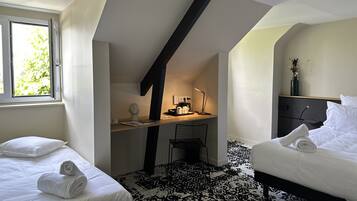 Een slaapkamer met twee bedden, een bureau, een stoel, een lamp en een raam met daglicht.