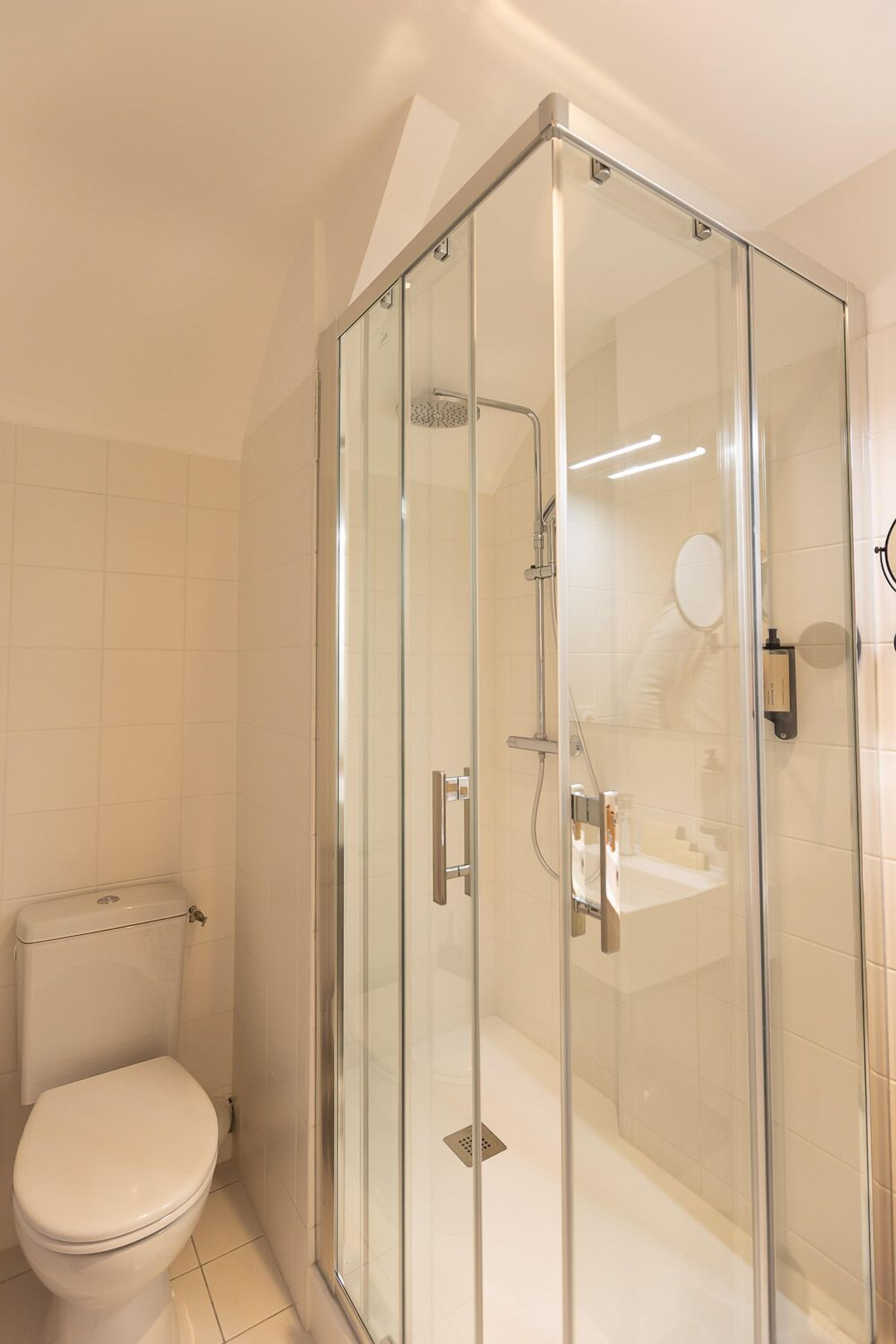 Un baño moderno con cabina de ducha de vidrio, inodoro y lavamanos.