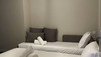 A hotel room with two beds, a hanging light fixture, and a visible power outlet on the wall.