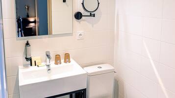 A modern bathroom with a white sink, mirror, and toilet.