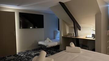 Habitación de hotel con cama, escritorio, silla, televisión y radiador.