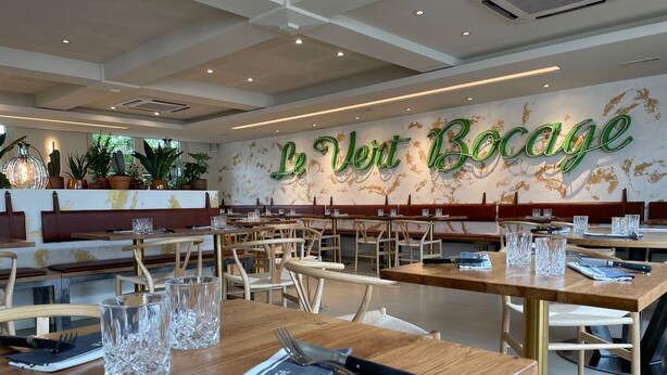 A restaurant interior with wooden tables, chairs, and a wall with 'Le Vent Bocage' written on it. - Le Vert Bocage (Franqueville-Saint-Pierre)