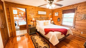 Un dormitorio de caba ña de madera con cama, mesita de noche, ventilador de techo y ventana.