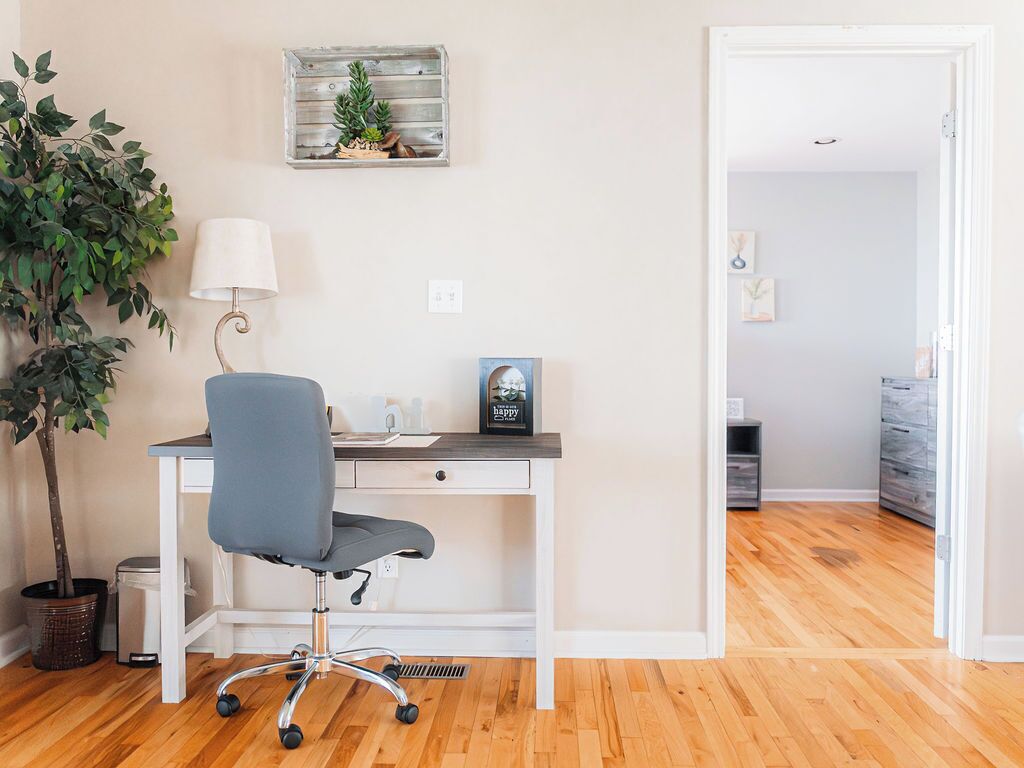 Un espace de bureau moderne comprenant un bureau, une chaise, une lampe, une plante en pot et un élément décoratif mural.