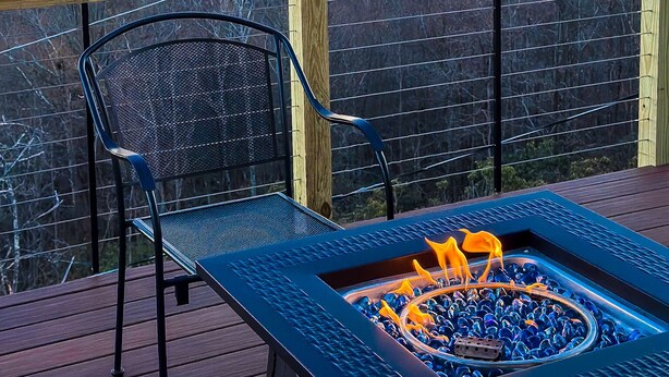 A deck with a fire pit and a chair, overlooking a scenic landscape. - "Mountain Escape" - Majestic Mountain Sunrises Near Blue Ridge Parkway & I-77 (Fancy Gap)