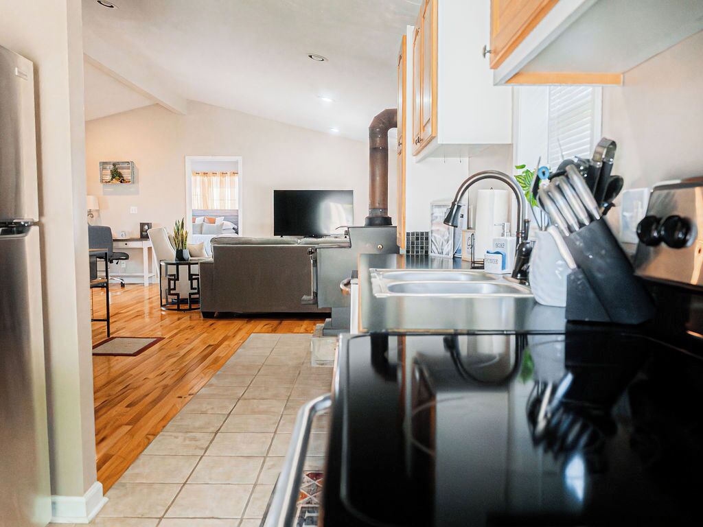 A modern kitchen with a stove, sink, and cabinets. There is a dining area with a table and chairs.