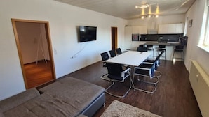 Un apartamento moderno con comedor, kitchenette y sala de estar con sofá y televisor.
