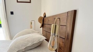 A bedroom with a wooden headboard, a bedside table with a glass container of seashells, and a lamp. - Special vacation villa  (San-Gavino-Di-Carbini)