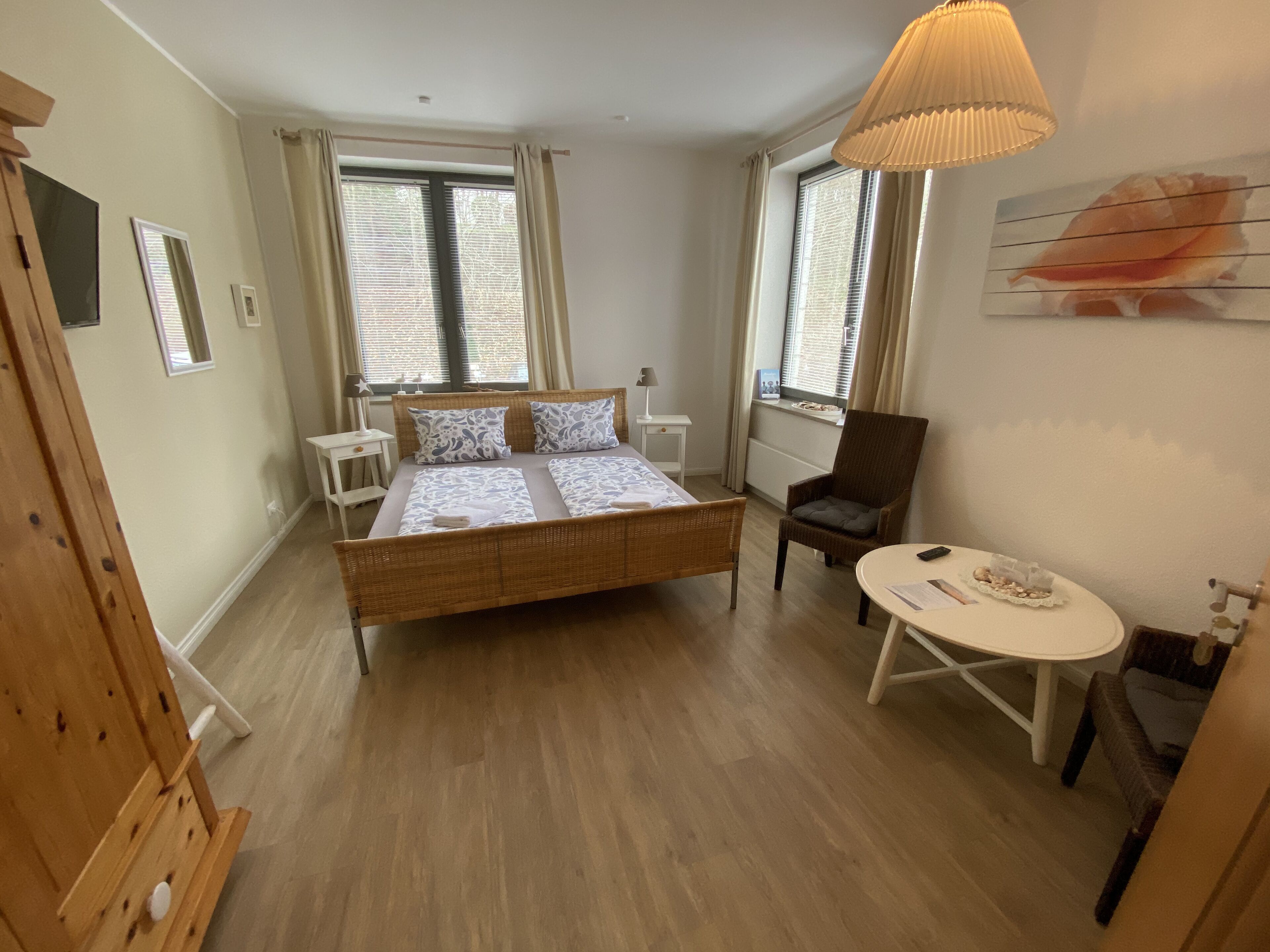 A bedroom with a large bed, a chair, a small table, and a lamp.