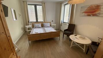 A bedroom with a large bed, a chair, a small table, and a lamp.