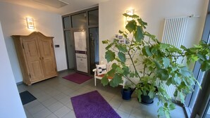 A hallway with a wooden wardrobe, a purple rug, a potted plant, and a door with a sign. - Gästehaus Lavendel (Flensburg)