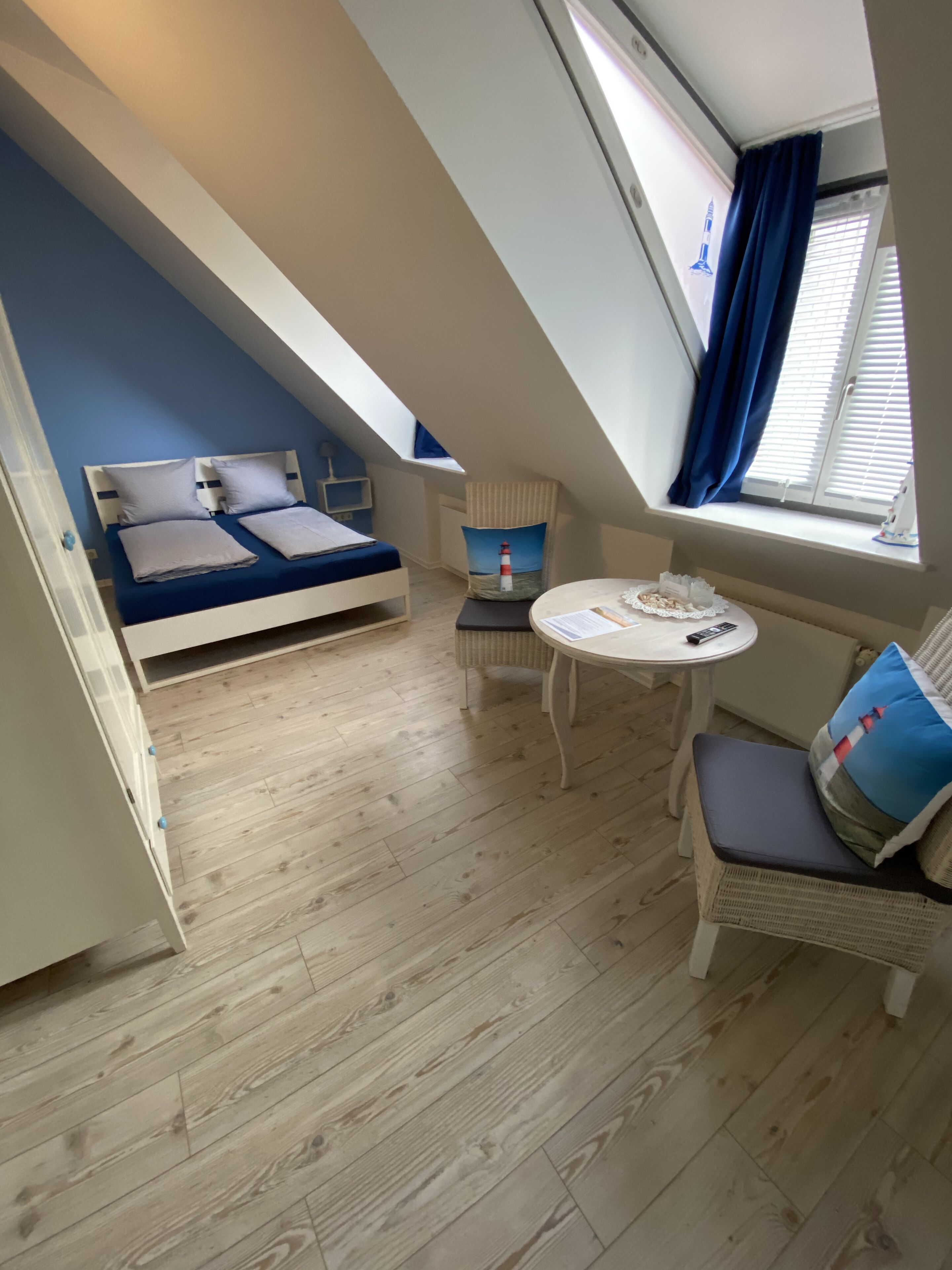Una habitación con cama doble alta, una mesita y una silla.