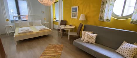 Una habitación con cama, sofá, mesa de comedor y una lámpara colgante.