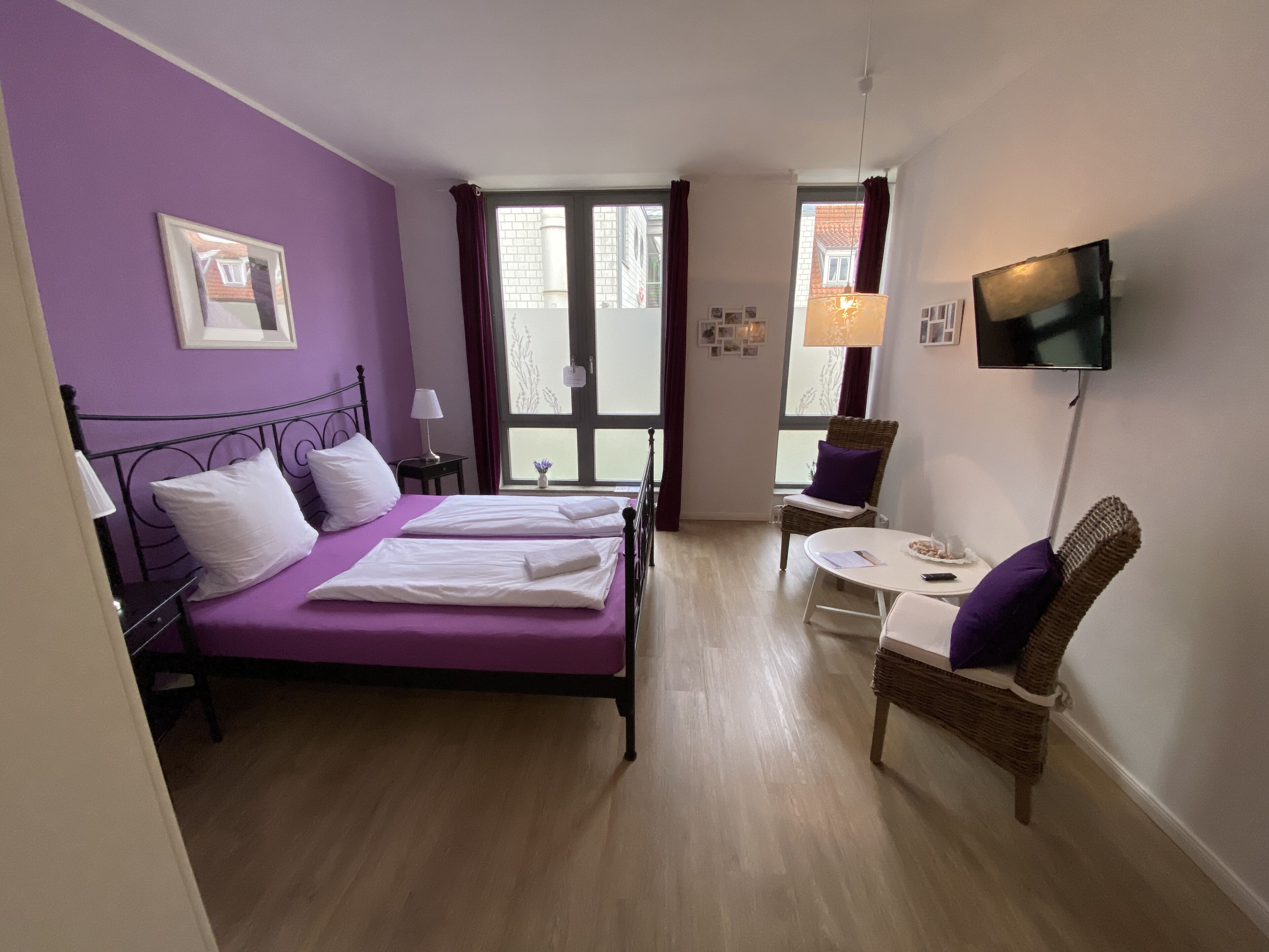 Una habitación con cama, una silla, una mesa, un televisor y una ventana.
