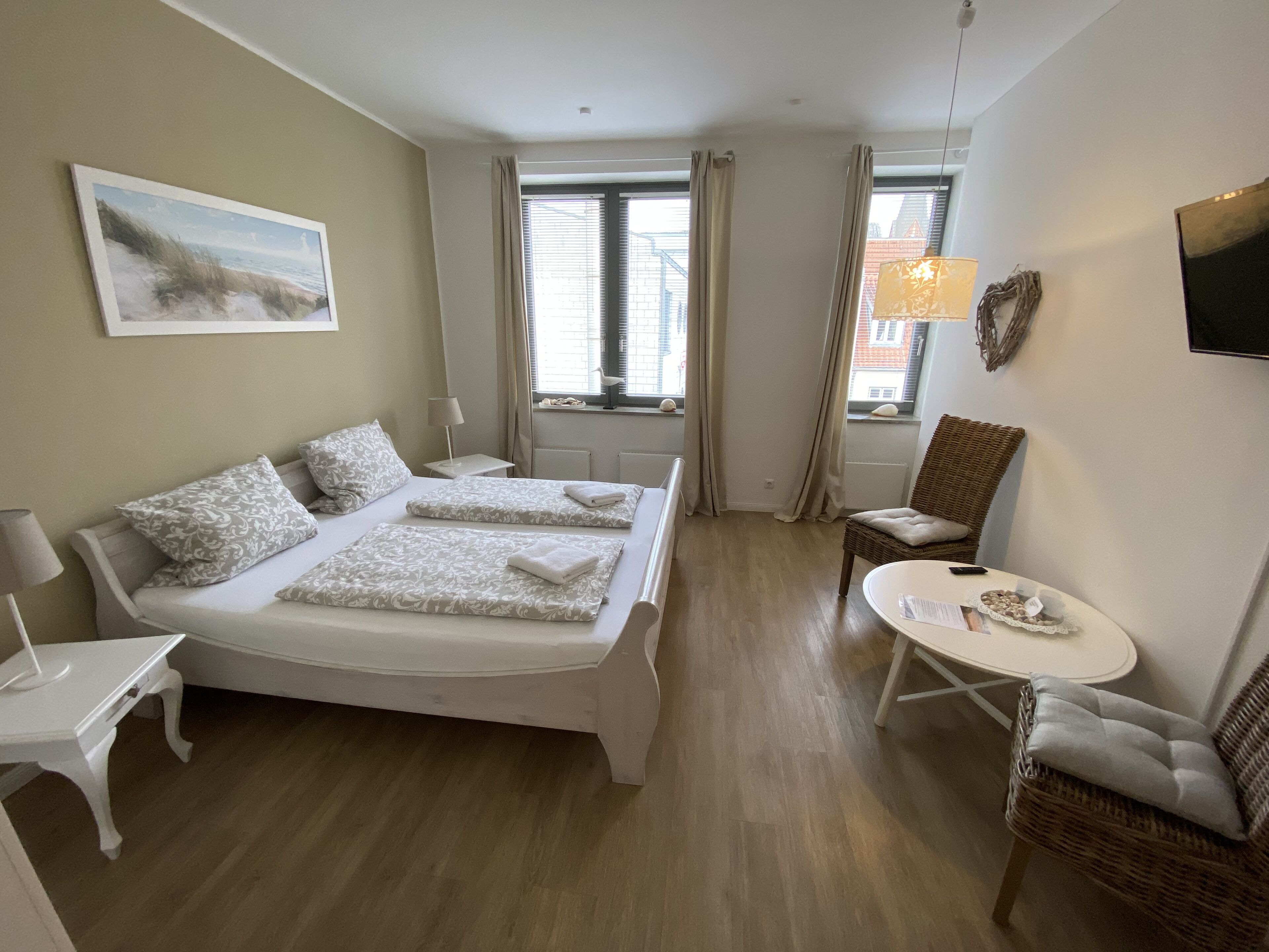 Une chambre d’hôtel avec un lit double, une petite table, une chaise et une fenêtre avec des rideaux.