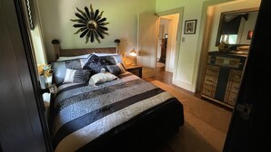 Een slaapkamer met een bed, een plafondventilator, een nachtkastje en een dressoir.
