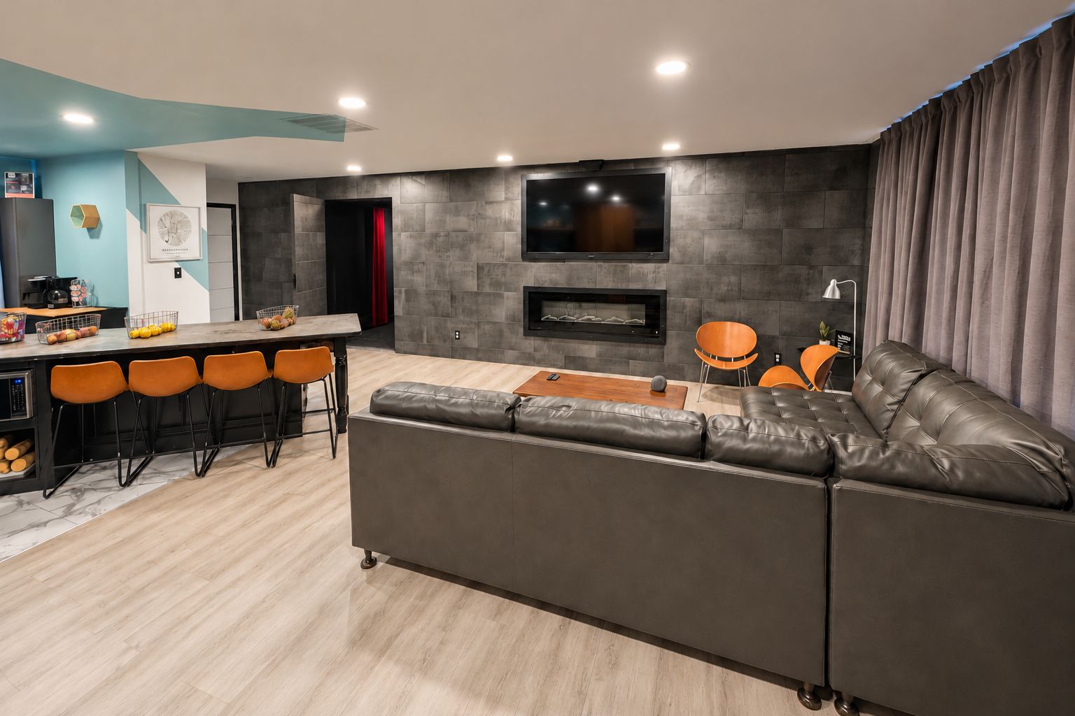 A modern living room with a grey leather sofa, a wooden coffee table, and a TV mounted on the wall.