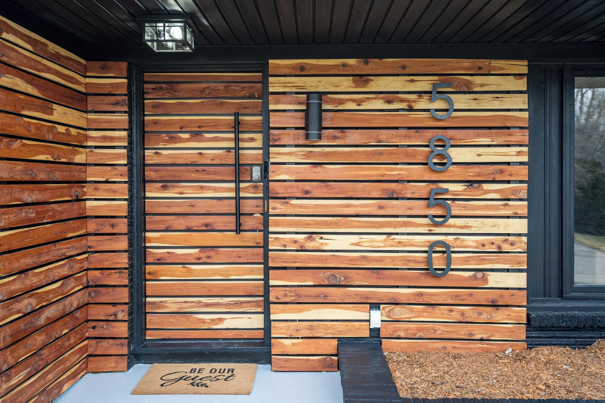 A modern building facade with a wooden panel design and a black door.