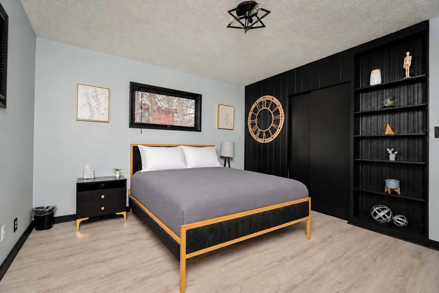 Un dormitorio con cama, mesitas de noche, un reloj de pared y una estantería.
